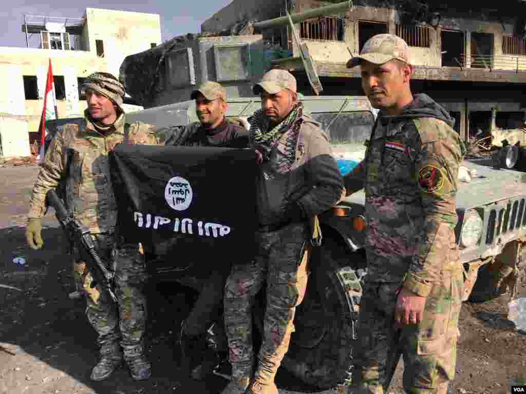 Iraqi forces hold up an Islamic State flag upside down, in Mosul, Iraq, Jan. 12, 2017. (K. Omar/VOA Kurdish)