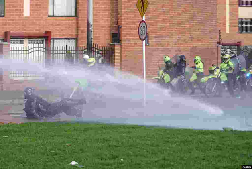 A police officer stumbles in a jet of water during anti-government protests in Bogota, Colombia, June 29, 2021.