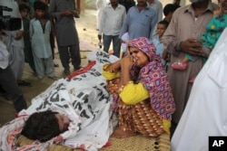 FILE - The mother of slain Pakistani social media star Qandeel Baloch mourns beside her dead body in Shah Sadderuddin, Pakistan, July 18, 2016. Baloch was killed by her brother for what he called “intolerable” behavior.