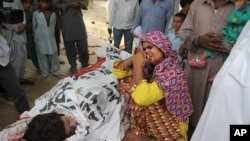 FILE - In this picture taken on July 18, 2016, the mother of Pakistani slain social media star Qandeel Baloch mourns besides her dead body in Shah Sadderuddin, Pakistan. Baloch was killed by her brother for what he called “intolerable” behavior.