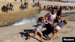 Maria Lila Meza Castro, center, a 39-year-old migrant woman from Honduras, runs away from tear gas with her 5-year-old twin daughters Saira Nalleli Mejia Meza, left, and Cheili Nalleli Mejia Meza near the border between the U.S. and Mexico, in Tijuana, Mexico, Nov. 25, 2018. 