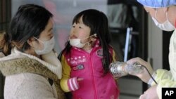 Mother and daughter receive radiation exposure scanning in Fukushima, northern Japan Friday, one week after a massive earthquake and tsunami, March 18, 2011
