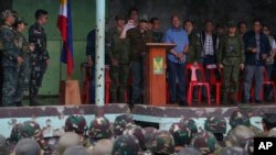 President Rodrigo Duterte (center, at podium) clenches his fist as he declares the liberation of Marawi after an almost five-months long battle to oust Islamic State fighters from the city, in Marawi, Philippines, Oct. 17, 2017.