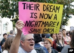 FILE - Judy Weatherly, a supporter of the Deferred Action for Childhood Arrivals program, holds up a sign during a protest outside the Federal Building in San Francisco, Sept. 5, 2017.