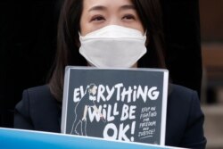 FILE - South Korean lawmaker Choi Hye Young holds a sign during a news conference indicating support for Myanmar's democracy, in front of the Myanmar Embassy in Seoul, March 10, 2021.