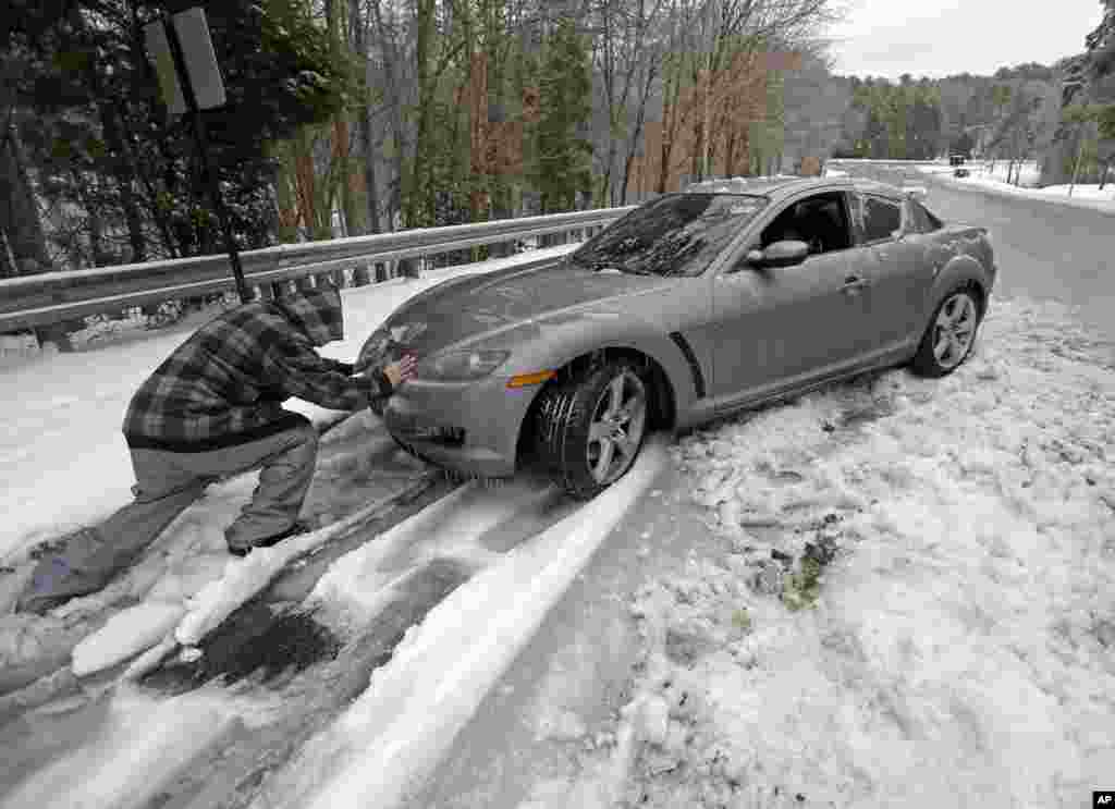 Một người qua đường giúp đẩy một chiếc xe từ lề đường đóng băng ở Chapel Hill, bang North Carolina, Mỹ. Người chủ phải bỏ chiếc xe lại trong đêm vì cơn bão mùa đông.