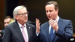 Presiden Komisi Uni Eropa Jean-Claude Juncker (kiri) berbicara dengan PM Inggris David Cameron pada KTT pemimpin Uni Eropa di Brussels, Belgia (18/2). 