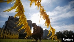 FILE - A man ties a yellow ribbon dedicated to victims onboard the sunken ferry Sewol, on a cable at Seoul City Hall Plaza, in Seoul.