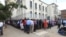 In this photo taken on Tuesday, May, 3, 2016, Zimbabweans wait in a long line to withdraw cash in Harare. Severe shortages of U.S dollars that are used as local currency have forced many residents into cash hunter-gatherers.