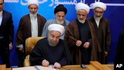 In this photo released by the office of the Iranian Presidency, President Hassan Rouhani signs the "Charter of Citizenship Rights" in Tehran, Dec. 19, 2016.