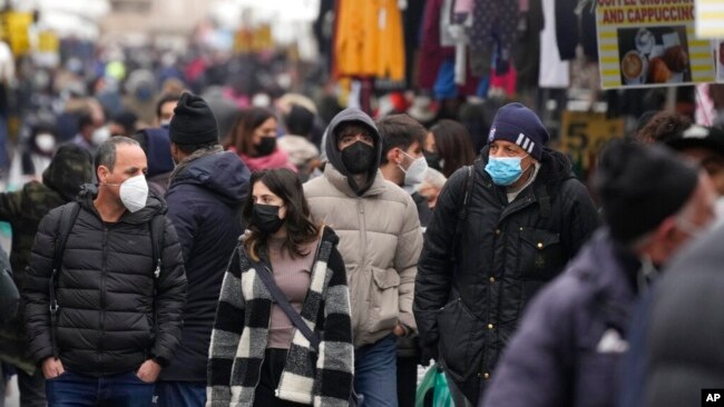 People, some wearing surgical masks, others FFP2 masks, to cope with the surge of COVID-19 cases stroll past stalls at the Porta Portese open air market, in Rome, Jan. 9, 2022.