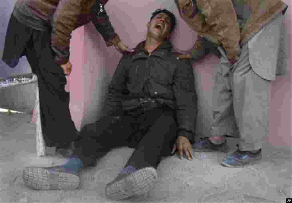 An Afghan man is comforted by relatives outside of a hospital in Kabul, Afghanistan, Tuesday, Dec. 6, 2011. A suicide bomber struck a crowd of Shiite worshippers marking a holy day Tuesday in the Afghan capital as scores of people were killed in an unprec