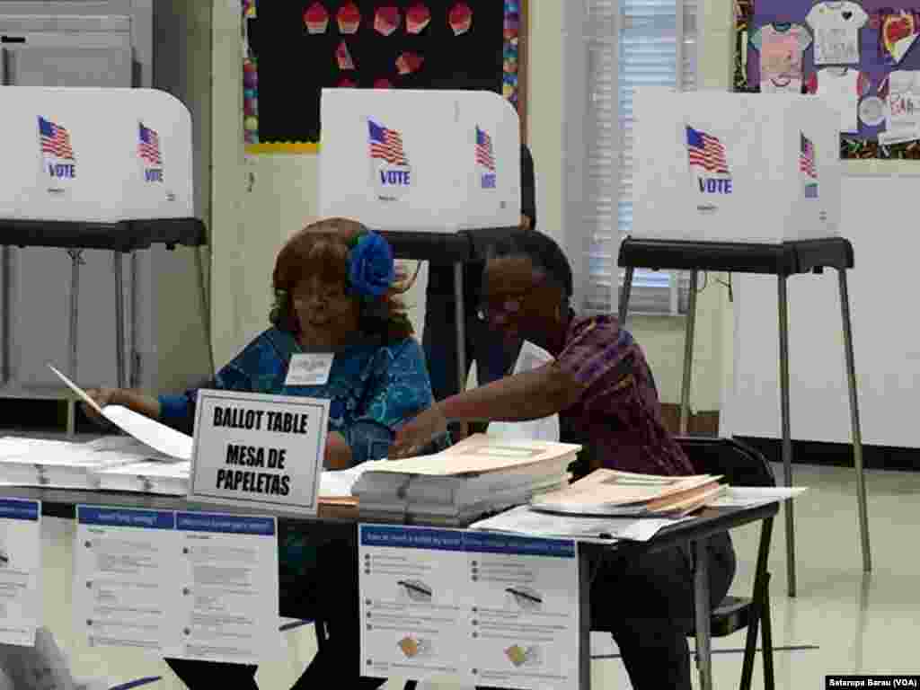Tenaga sukarela memeriksa dokumen-dokumen di sebuah tempat pemungutan suara (TPS) di Sekolah Dasar Watkins Mill, Montgomery Village, negara bagian Maryland (26/4).