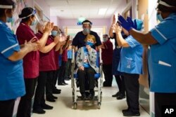 Margaret Keenan, 90, is applauded by staff as she returns to her ward after becoming the first patient in the UK to receive the Pfizer-BioNTech COVID-19 vaccine, at University Hospital, Coventry, England.
