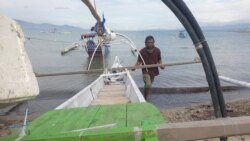 Mansur (40), saat sedang mendorong perahunya usai melaut di teluk Palu, Sulawesi Tengah. Sabtu, pagi, 19 Desember 2020. (Foto: VOA/Yoanes Litha)