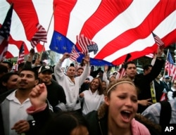 FILE - Participants in an immigration rights rally walk under a giant American flag during a march through downtown Chicago.