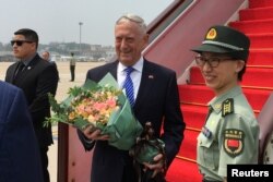 U.S. Defense Secretary Jim Mattis receives a bouquet upon arrival at an airport in Beijing, China, June 26, 2018.