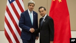 U.S. Secretary of State John Kerry, left, shakes hands with Chinese Foreign Minister Wang Yi as they pose for photos before their meeting at the 47th ASEAN Foreign Ministers' Meeting in Naypyitaw, Myanmar, Aug. 9, 2014.