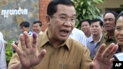 Cambodian Prime Minister Hun Sen gestures with an inked finger after casting his ballot in local elections at Ta Khmau town, in Kandal province, some 15 kilometers (9 miles) south of Phnom Penh, Cambodia, Sunday, June 3, 2012.