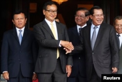 Cambodia's Prime Minister Hun Sen (2nd R) shakes hands with Sam Rainsy (2nd L), president of the Cambodia National Rescue Party (CNRP), after a meeting at the Senate in central Phnom Penh July 22, 2014. Sen and Rainsy met at the Senate in an attempt to solve the country's year-long political crisis after a disputed election. Seven members of parliament and an assistant, all members of CNRP, were ordered detained pending trial and taken to prison on charges of leading an insurrection, which carries a penalty of 20 to 30 years in prison, and incitement to violence. REUTERS/Stringer