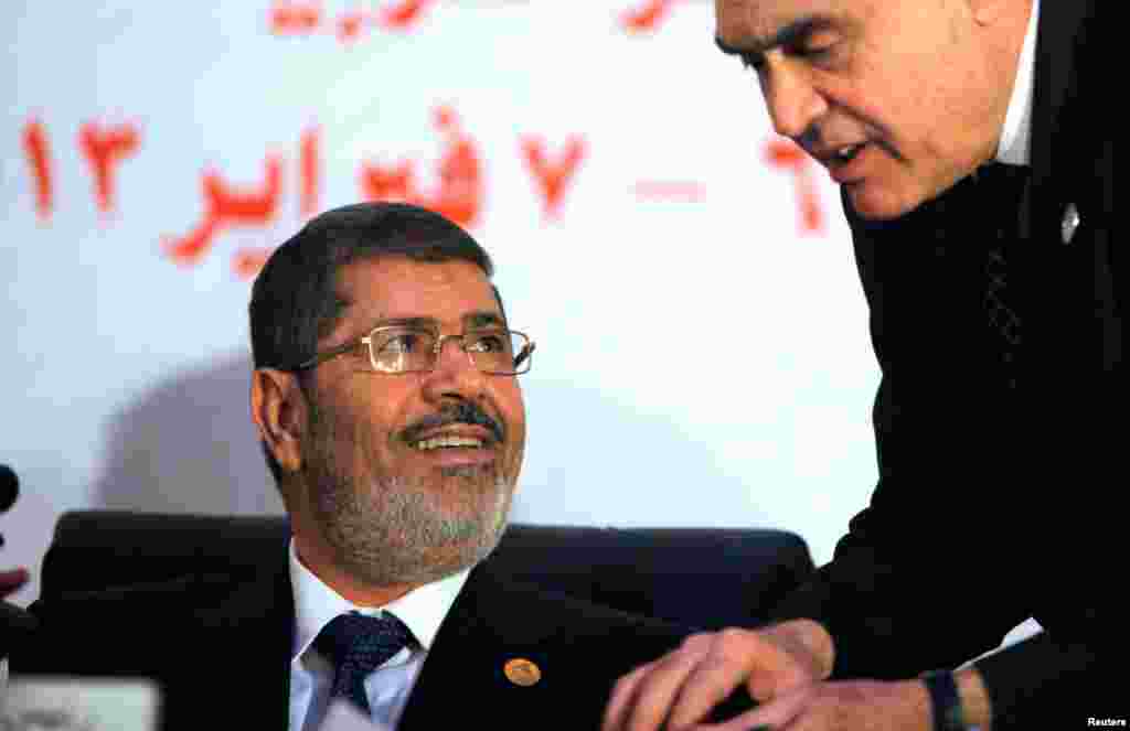 Egyptian President Mohammed Morsi listens to his Foreign Minister Mohammed Kamel Amr during the opening of the 12th summit of the Organization of Islamic Cooperation (OIC) in Cairo, Egypt, February 6, 2013. 