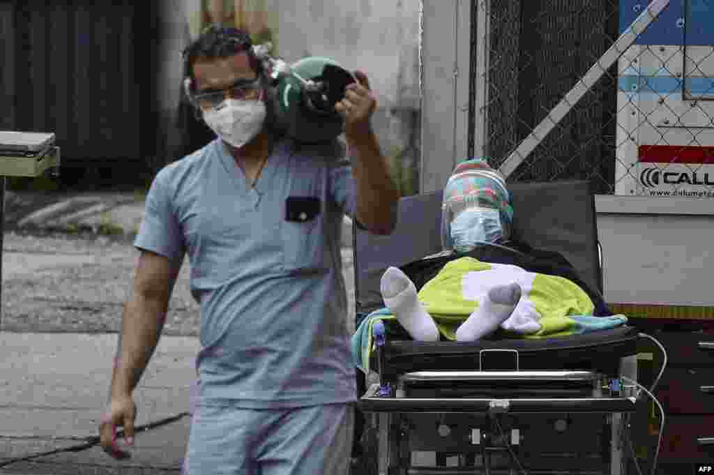 A doctor carries an oxygen tank after disconnecting a man infected with COVID-19 from it at a field hospital set up in the yard of the School Hospital in Tegucigalpa, June 17, 2020.