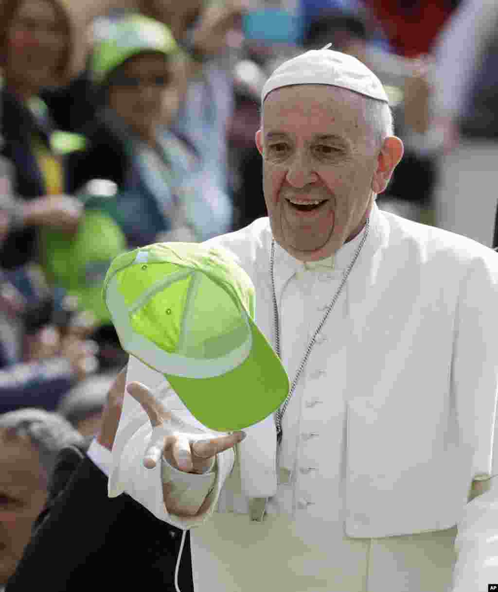 پاپ فرانسیس کلاهی را می گیرد که یکی از حامیانش به سمتش در حاشیه سخنرانی هفتگی اش در سنت پیترز واتیکان پرتاب کرده است.