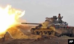 This frame grab from video provided Nov. 8, 2017, by the government-controlled Syrian Central Military Media, shows a tank firing on militants' positions on the Iraq-Syria border.