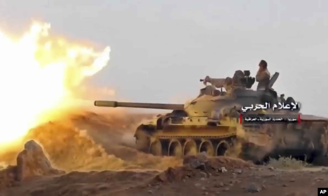 This frame grab from video provided Nov. 8, 2017, by the government-controlled Syrian Central Military Media, shows a tank firing on militants' positions on the Iraq-Syria border.