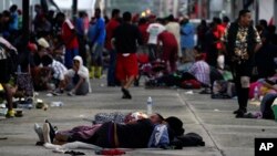 Los migrantes, en su mayoría de Centroamérica, duermen en la calle en Huixtla, estado de Chiapas, México, al amanecer del martes 26 de octubre de 2021, mientras aprovechan el día para descansar durante su caminata a pie hacia EE. UU.