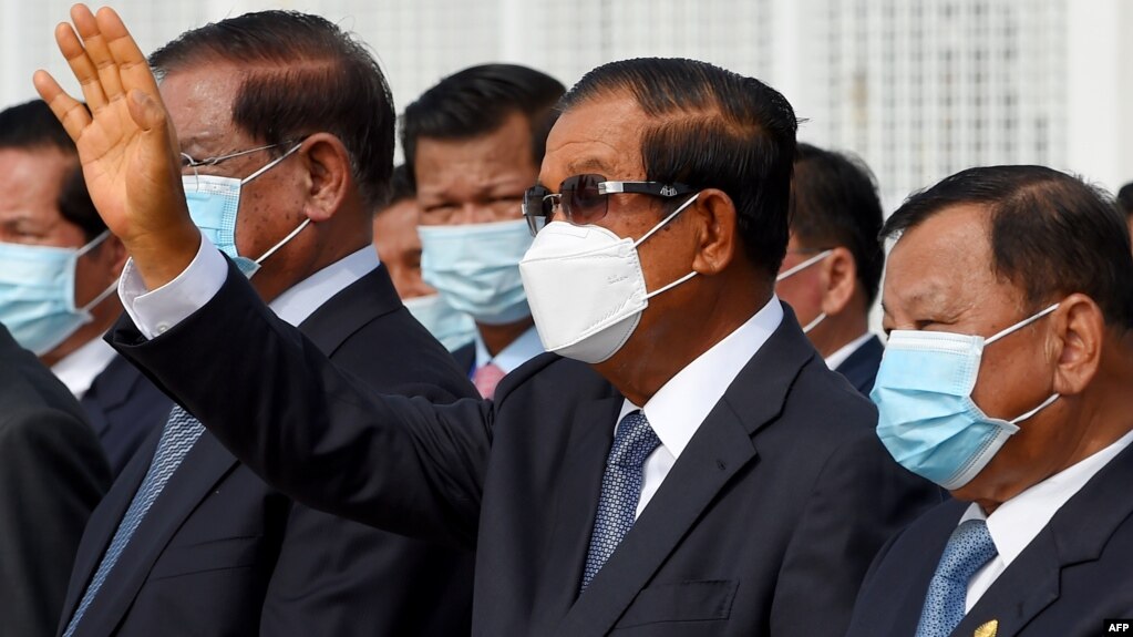 រូបឯកសារ៖ ​លោក​នាយករដ្ឋមន្ត្រី ហ៊ុន សែន (លើក​ដៃឡើង) ឈរ​ជាមួយ​នឹង​មន្ត្រី​កំពូលៗ​របស់​លោក​មួយ​ចំនួន ក្នុង​អំឡុងពេល​ជូន​ដំណើរ​ព្រះមហាក្សត្រ​ព្រះអង្គ សីហមុនី យាង​ចេញ​ដំណើរ​ទៅ​កាន់ប្រទេស​ចិន​ដើម្បី​ពិនិត្យ​សុខភាព អាកាសយានដ្ឋាន​ភ្នំពេញ ថ្ងៃទី៦ ខែតុលា ឆ្នាំ២០២០។