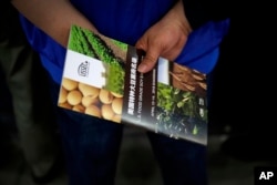 FILE - A Chinese visitor holds a U.S. soybean company's leaflet at the international soybean exhibition in Shanghai, April 12, 2018.