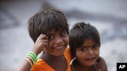 Two Indian girls react to the camera as they play on a street outside their roadside shanty, on International Day of the Girl Child in Hyderabad, India, Oct. 11, 2012.