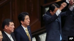 Japanese Prime Minister Shinzo Abe, center left, Minister in charge of regional issues Shigeru Ishiba, second left, listen as lawmakers of the House of Representatives shout a banzai cheer after the parliament was dissolved for a general election in Tokyo