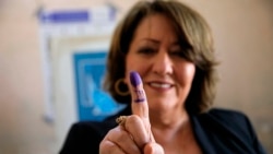 A woman shows her ink-marked finger after casting her vote inside a polling station in the country's parliamentary elections in Basra, Iraq, Oct. 10, 2021.