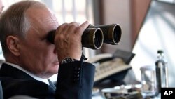 FILE - Russian President Vladimir Putin holds binoculars while watching military exercises at "Telemba" training ground about 80 kilometers (50 miles) north of the city of Chita in eastern Siberia, Russia, Sept. 13, 2018. 