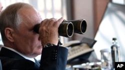 FILE - Russian President Vladimir Putin holds binoculars while watching military exercises at "Telemba" training ground about 80 kilometers (50 miles ) north of the city of Chita in eastern Siberia, Russia, Sept. 13, 2018. 
