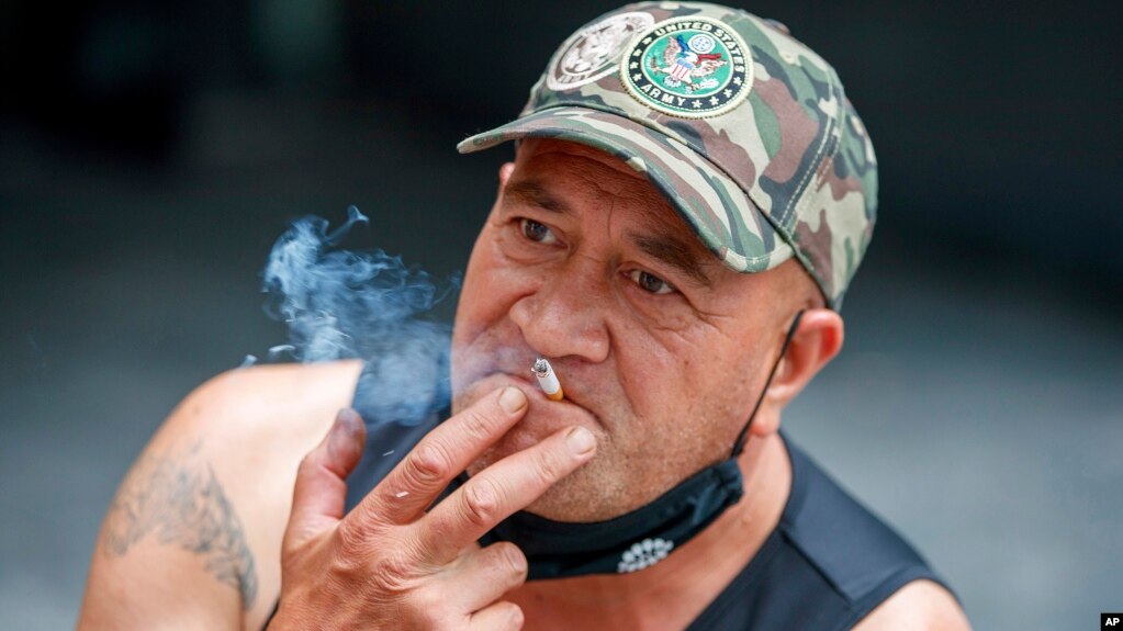 New Zealand Smoking BanA man sits while smoking in Auckland, New Zealand, Thursday, Dec. 9, 2021. New Zealand's government believes it has come up with a unique plan to end tobacco smoking, a lifetime ban for those aged 14 and under. (AP Photo/David Rowland)