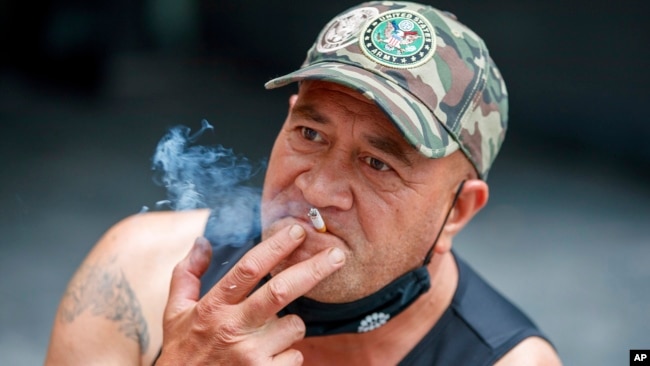 New Zealand Smoking BanA man sits while smoking in Auckland, New Zealand, Thursday, Dec. 9, 2021. New Zealand's government believes it has come up with a unique plan to end tobacco smoking, a lifetime ban for those aged 14 and under. (AP Photo/David Rowland)