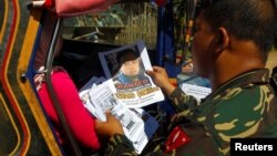 FILE - Soldiers distribute pictures of a member of extremist group Abu Sayyaf, Isnilon Hapilon, in Butig, Lanao del Sur in southern Philippines, Feb. 1, 2017. Hapilon was thought to be working with one of the Islamic State operatives targeted by the U.S. Friday.