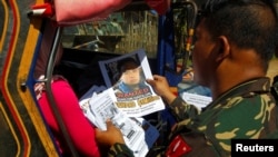 FILE - Soldiers distribute pictures of a member of extremist group Abu Sayyaf, Isnilon Hapilon, who has a U.S. government bounty of $5 million for his capture, in Butig, Lanao del Sur in southern Philippines, Feb. 1, 2017.