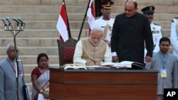 India's new prime minister Narendra Modi, center, signs after taking the oath of office at the presidential palace in New Delhi, India, Monday, May 26, 2014. Modi's inauguration is the first to which India invited leaders from across South Asia. (AP Phot