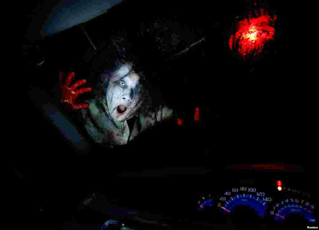 An actor dressed as a zombie performs during a drive-in haunted house show, performed by Kowagarasetai (Scare Squad), for people inside a car in order to maintain social distancing amid the spread of the coronavirus disease, at a garage in Tokyo, Japan.
