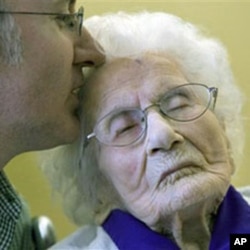 Besse Cooper, 114, right, receives a kiss from her grandson Paul Cooper, 42, during a ceremony in which Guinness World Records recognized her as the word's oldest living person - and now now hold the title of oldest living North American - at the nursing