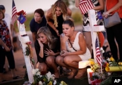 FILE - Mourners visit a makeshift memorial for victims of a mass shooting in Las Vegas, Oct. 6, 2017.