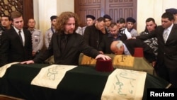 Omar Chatah, son of former Lebanese minister Mohamad Chatah, who was killed in a bomb blast on Friday, stands next to his father's coffin during his mass funeral at al-Amin mosque in Martyrs' Square in downtown Beirut, Dec. 29, 2013.