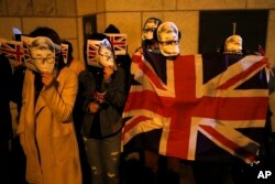 香港示威者头戴曾被中国拘留的英国前驻港总领馆雇员郑文杰头像面罩在英国驻港总领馆前举行集会。（2019年11月29日）