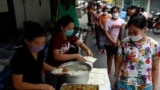မြန်မာရွှေ့ပြောင်း အလုပ်သမားတွေကို အလှူရှင်တချို့က အစားအစာ လှူဒါန်းနေပုံ။ (ဓာတ်ပုံ - ရိုက်တာ) 