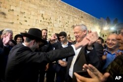 Leader of the Blue and White party, former Israeli army chief of staff, Benny Gantz, right, dances with ultra Orthodox Jewish men at the Western Wall, in Jerusalem's Old City, March 28, 2019.