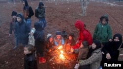 FILE - Refugees, who fled the violence in northern Syria, huddle around a fire in the Syrian village of Akda hoping to cross into Turkey, Jan. 23, 2016. Turkey's border guards prevented them from approaching the border, activists said.